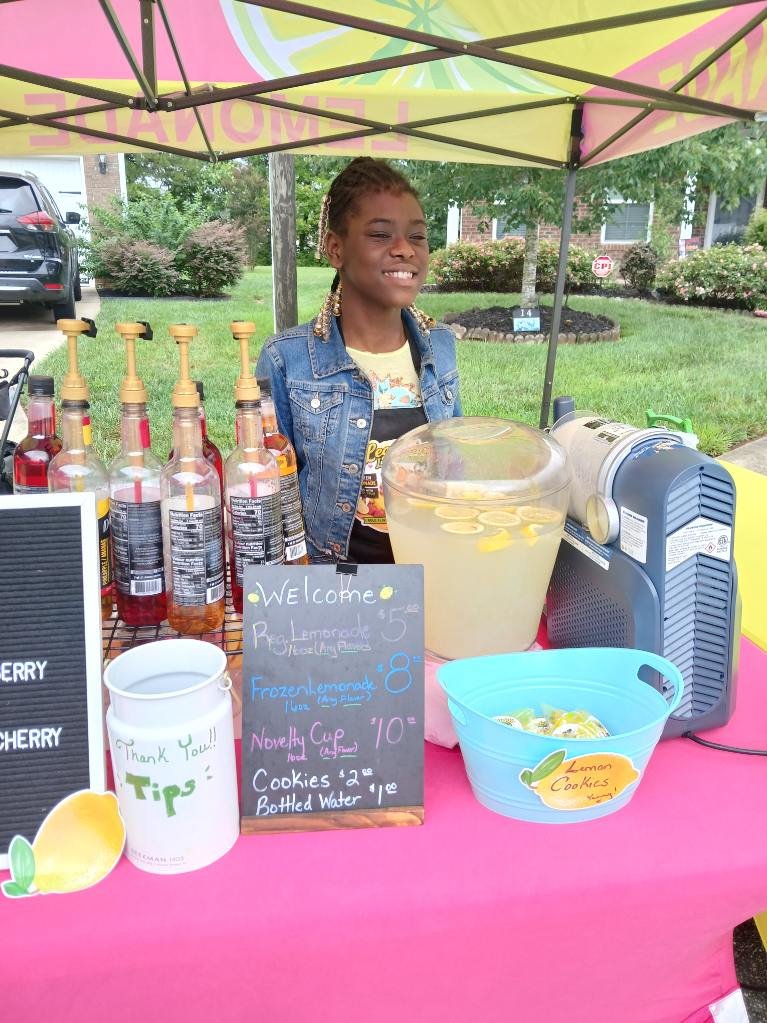 A Legendary Lemonades stand operator smiling behind the table