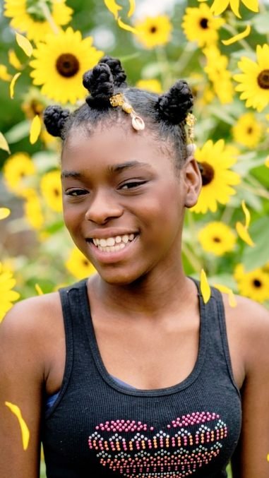 One of the sisters smiling in a sunflower field